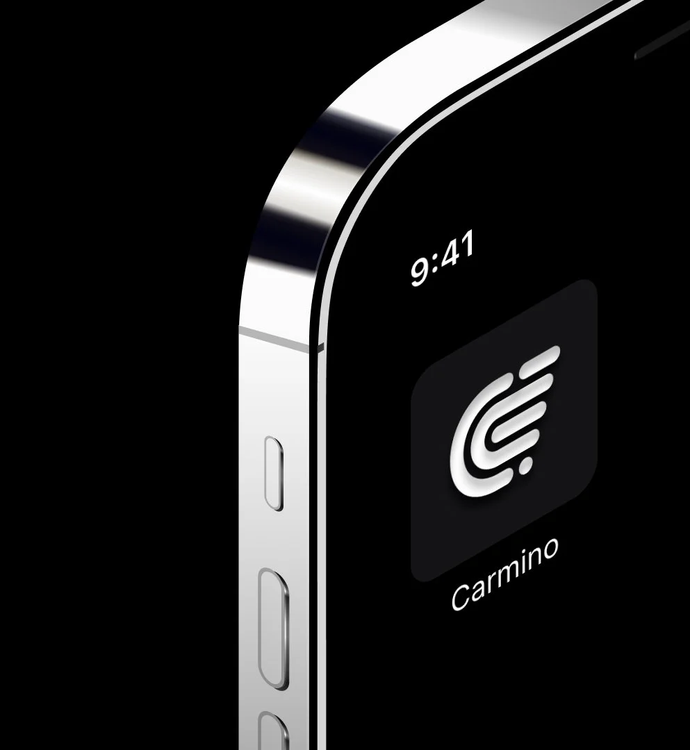 The Carmino app icon on a close-up of a silver phone against black.